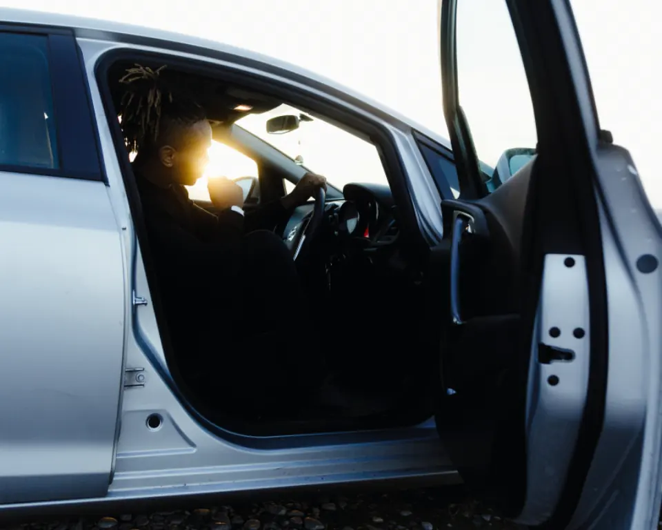 A car with its driver door standing open in bright daylight