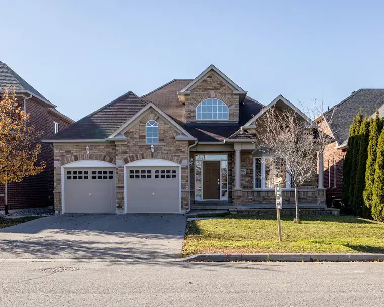 A brick family home with a double garage and a front lawn